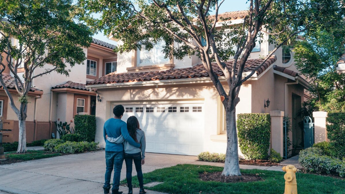 Couple hugging outside their newly purchased suburban home, showcasing togetherness and new beginnings.