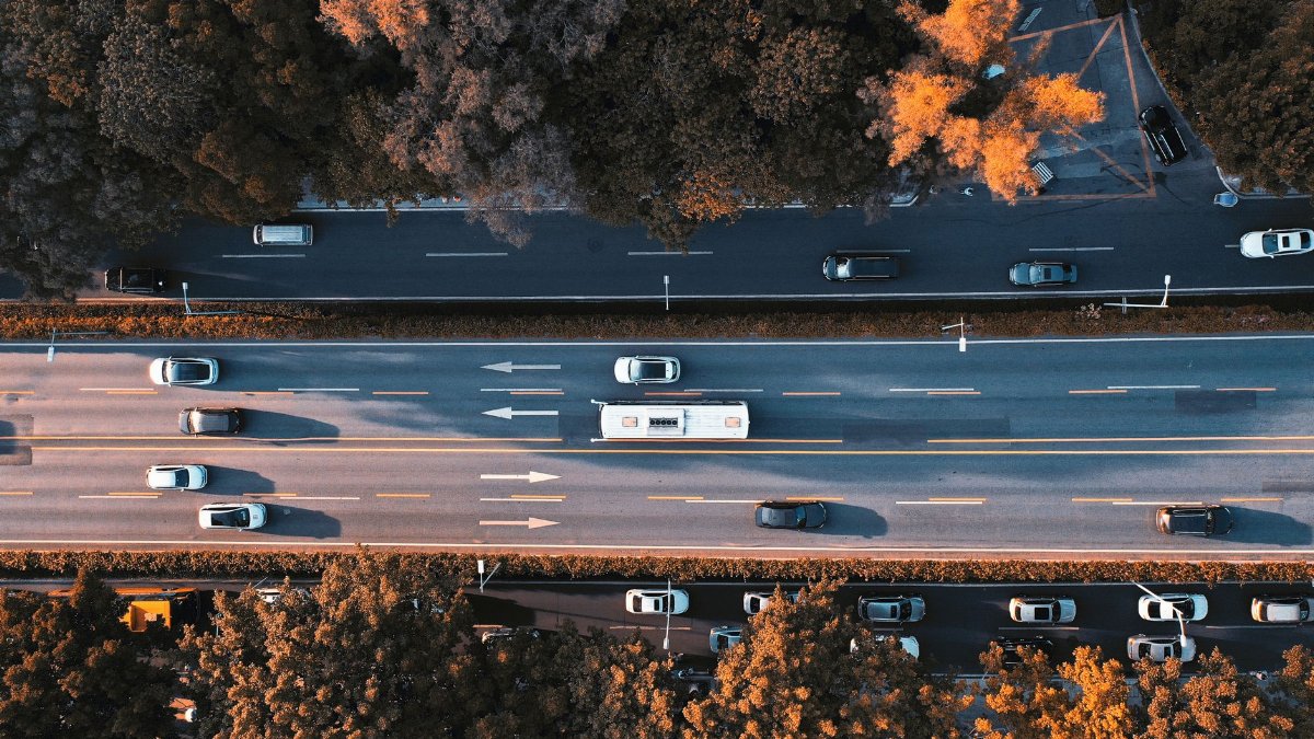 Drone shot of a busy road in Guangzhou, China, during autumn with cars and vibrant foliage.