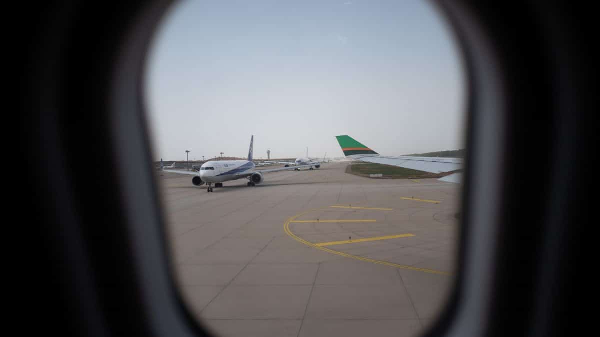 Airplane seen through a window, parked on the airport runway, capturing a travel moment.