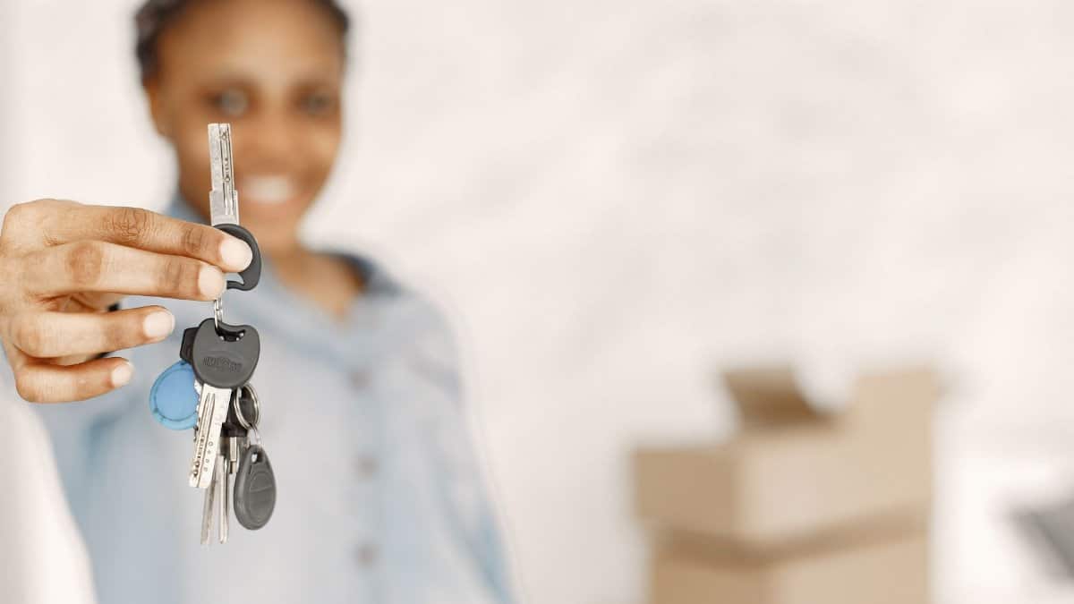 Close-up of a woman holding keys with a blurred background, symbolizing a new home or real estate concept.