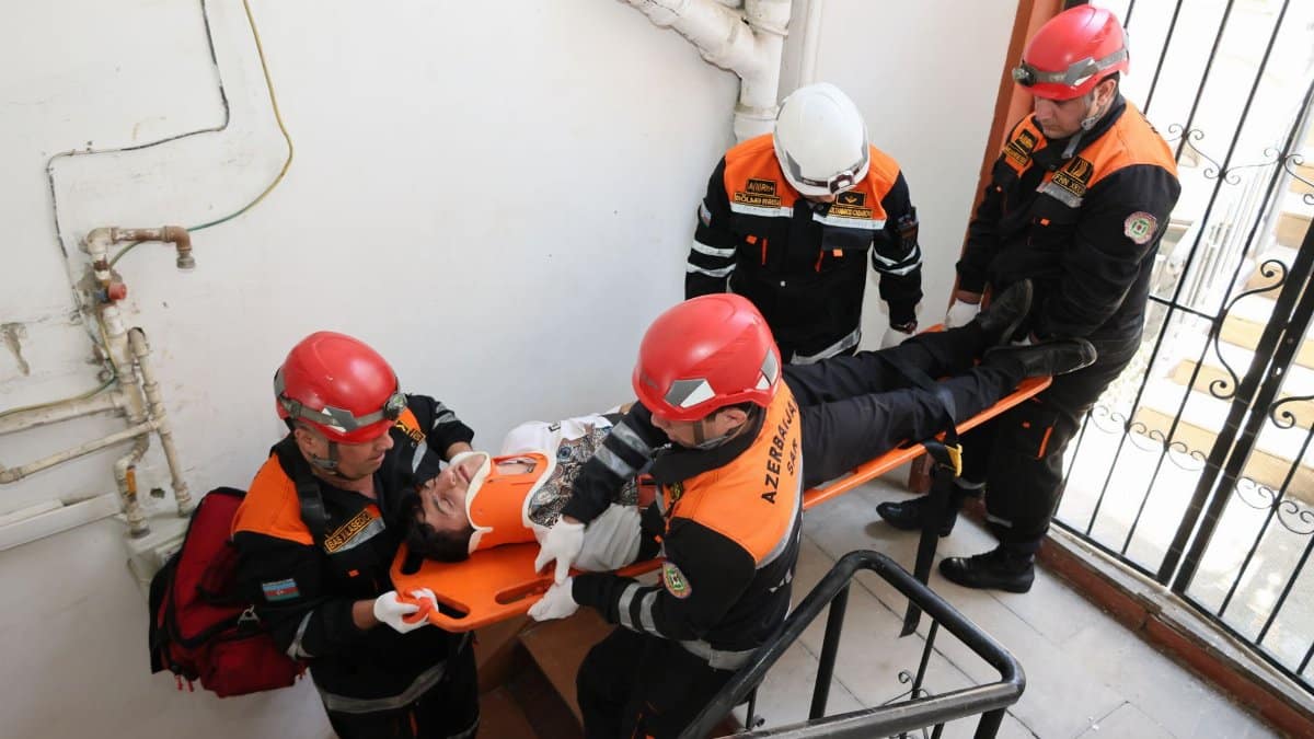 Emergency responders in action carrying an injured person down a staircase with teamwork.