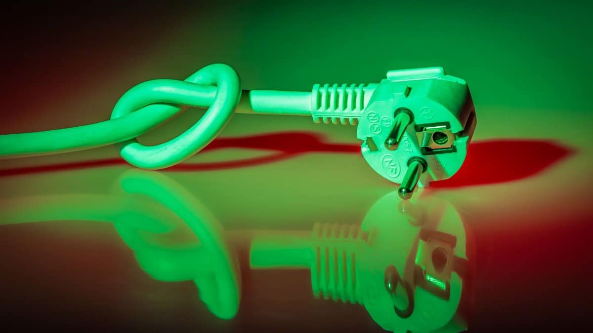 A knotted electrical plug showing reflection with vibrant lighting effects.