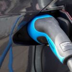 Close-up of an electric vehicle being charged using a Mennekes EV connector.
