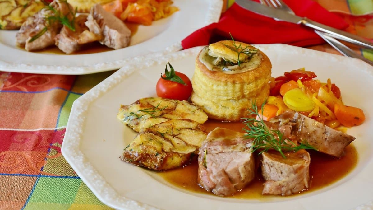 Elegant pork tenderloin with vegetables, puff pastry, and tomato garnish, perfect for gourmet dining.