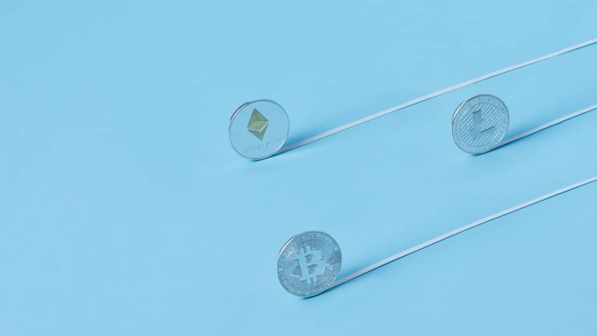 Minimalist image of Bitcoin, Ethereum, and Litecoin coins on a baby blue background.