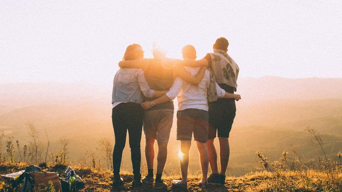 A group of friends embrace while enjoying a breathtaking sunrise over the Brazilian highlands.