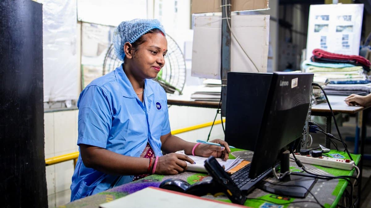 Female factory worker inputs data in a textile manufacturing setting. Indoors and focused.