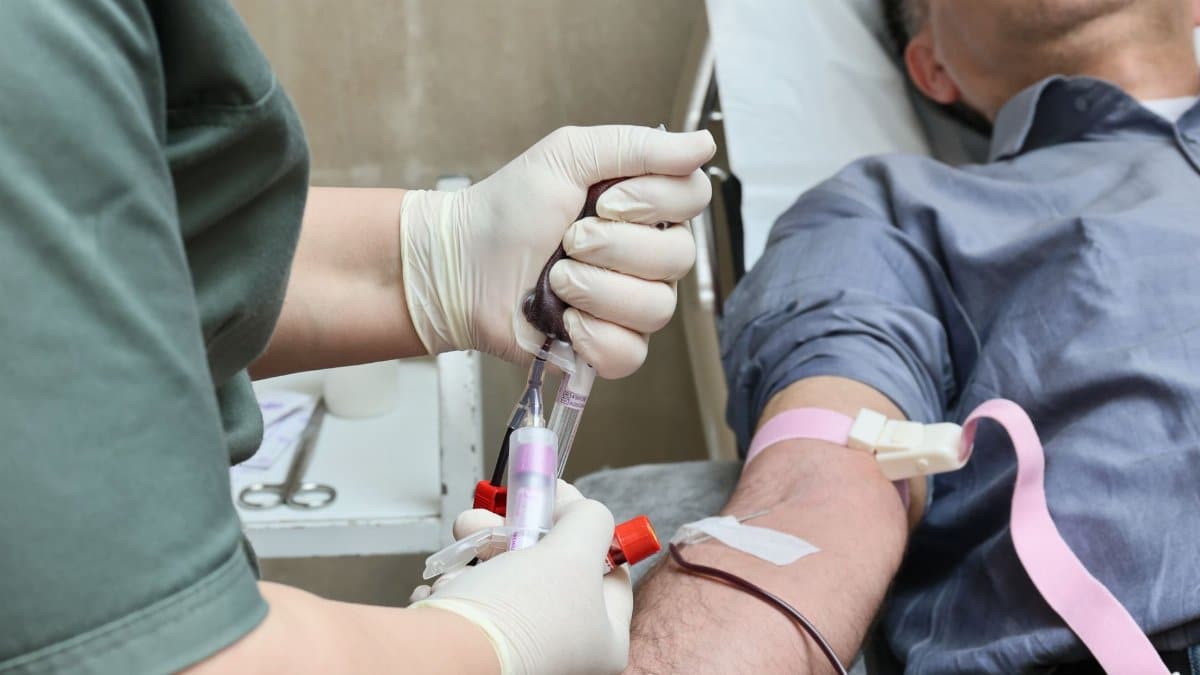 A healthcare professional drawing blood from a donor’s arm using a syringe.