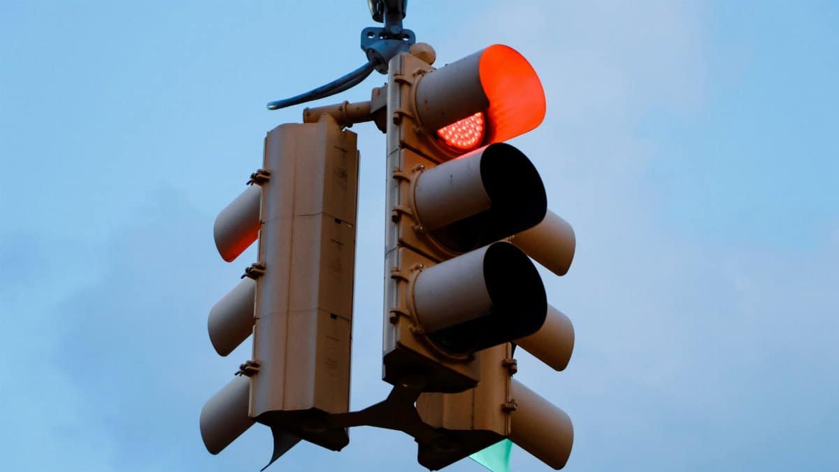 Close-up of a red traffic light signaling stop against a clear blue sky.