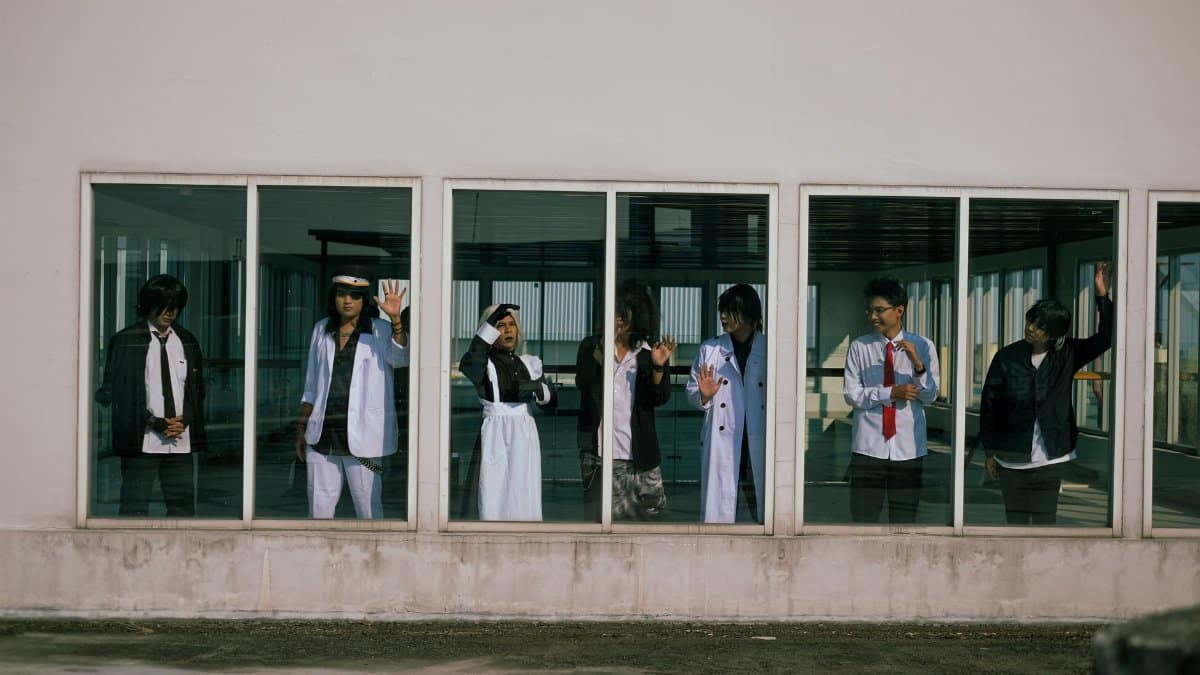 Group of young adults in diverse outfits seen through large windows in an urban setting.