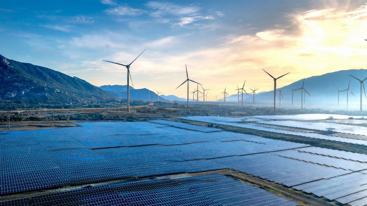 Stunning landscape featuring solar panels and wind turbines at sunrise, symbolizing sustainable energy.
