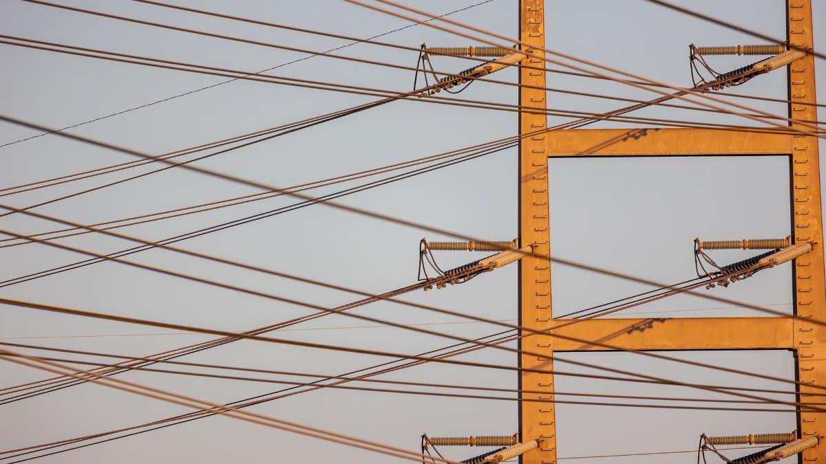 High voltage power lines with sunset sky background, illustrating energy distribution.