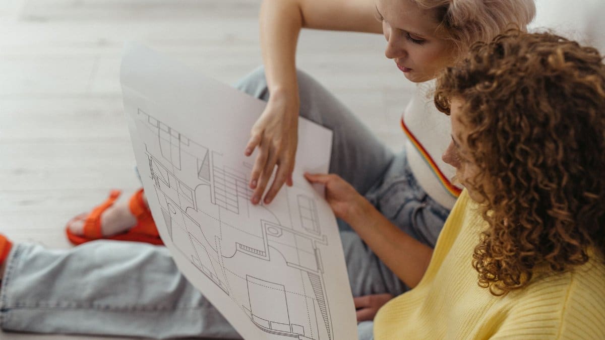Two women discussing and planning with a floor plan indoors.
