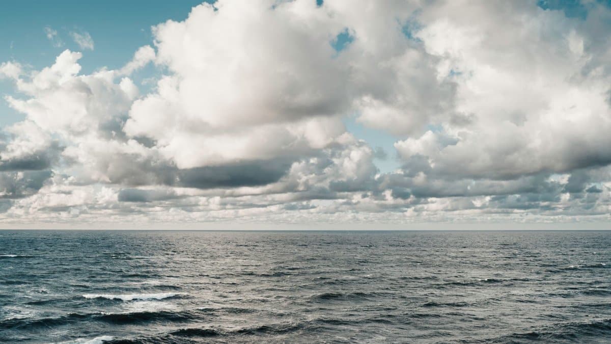 Waves crashing under a dramatic sky with thick clouds over the ocean, showcasing nature's beauty.