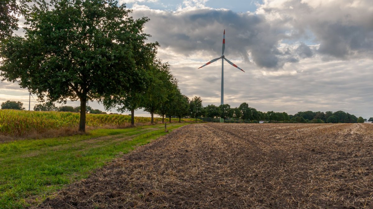 Wind turbine amidst a picturesque field under a cloudy sky in Coesfeld, Germany.