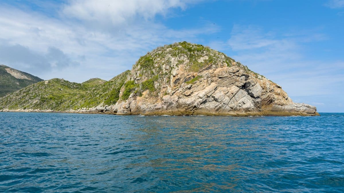 Beautiful view of a rocky island surrounded by clear blue ocean and sky, perfect for travel and nature lovers.