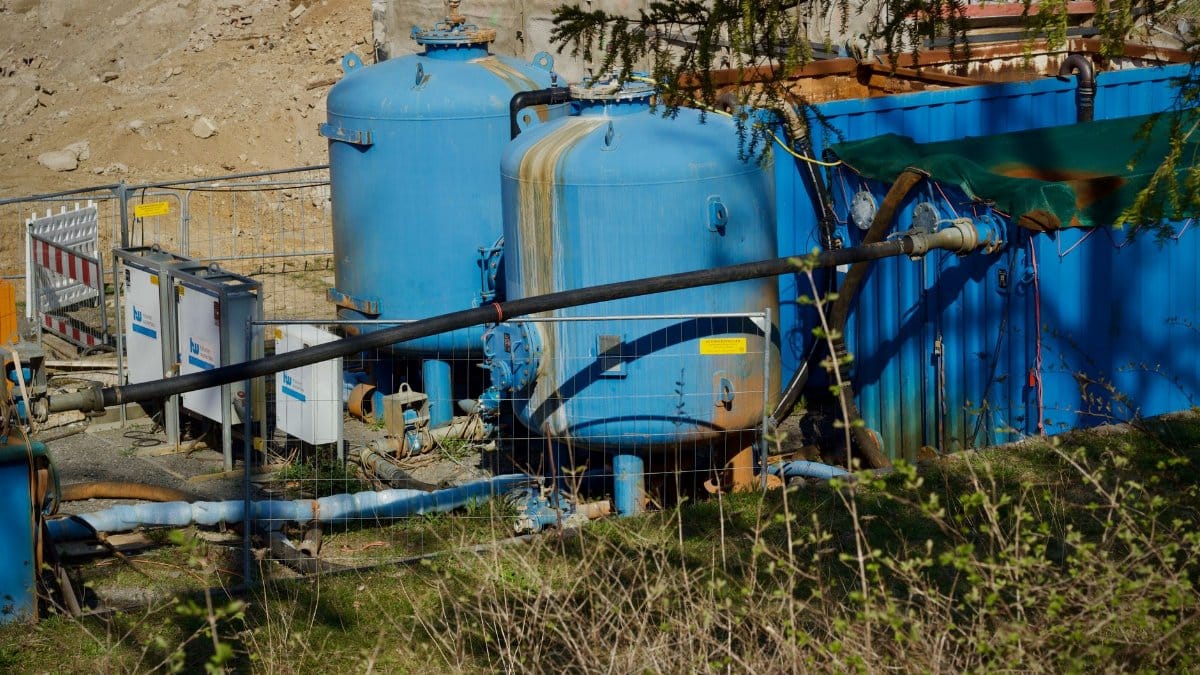 Outdoor industrial water filtration plant with large blue tanks under sunlight.