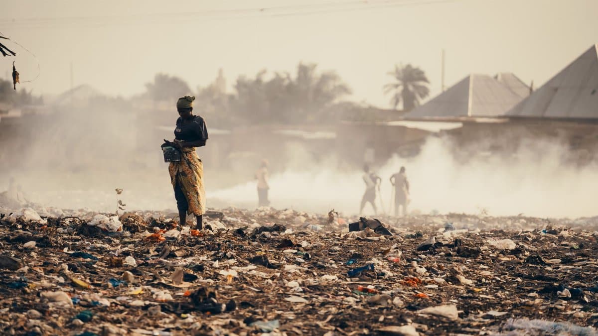 A scene of environmental pollution in Burundi with people amidst plastic waste and smoke.