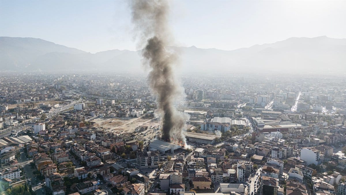 An aerial view of a smoke plume over Denizli, Türkiye, highlighting urban landscapes and mountain backdrop.