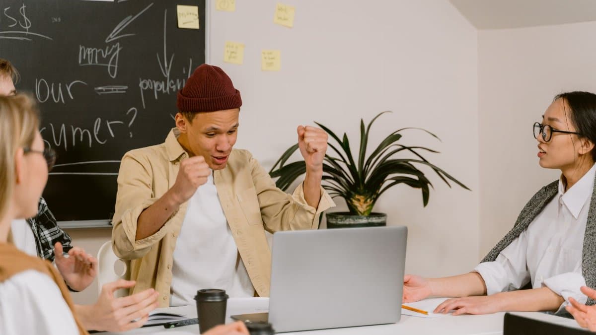 A diverse team of young professionals celebrating success in a modern office environment.