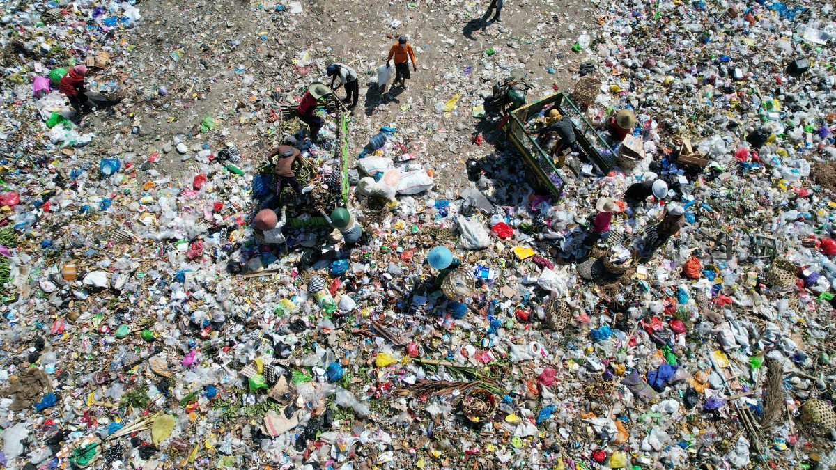 Aerial photo showing people sorting through waste in a landfill, highlighting environmental issues.