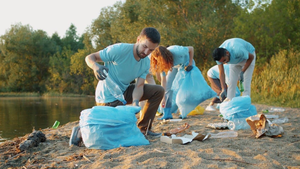 Group of eco-conscious volunteers removing trash from a riverbank for environmental preservation.