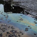 A vivid iridescent oil spill on rough asphalt surface, highlighting environmental contamination.