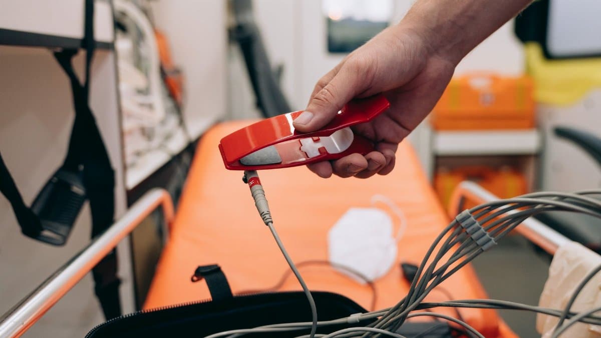 A paramedic holding medical equipment inside an ambulance, ready for emergency care.