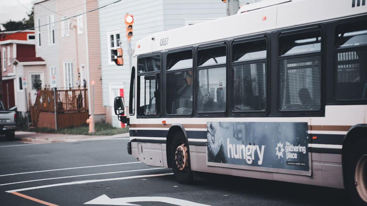 City bus making a turn at an urban intersection with traffic lights and residential buildings.