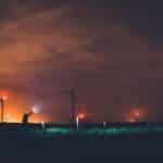 Silhouette of a person near wind turbines at night under cloudy sky in Texas.
