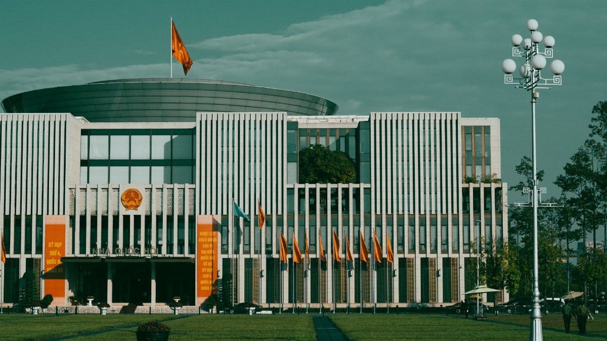 Front view of the National Assembly building in Hanoi, showcasing its modern architecture and national flags.