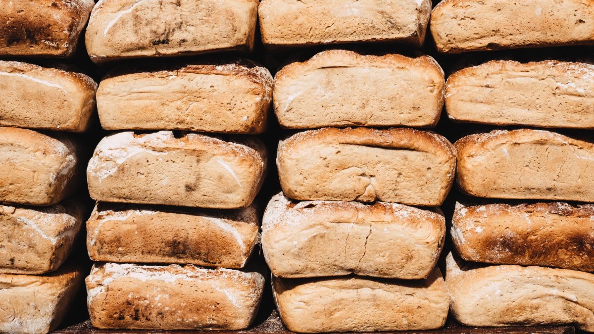 A stack of freshly baked rustic bread loaves on a wooden board. Perfect for bakery promotions.