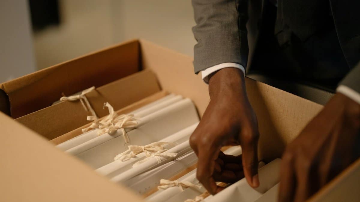 Close-up of a professional arranging tied documents inside a box, symbolizing organization and efficiency.