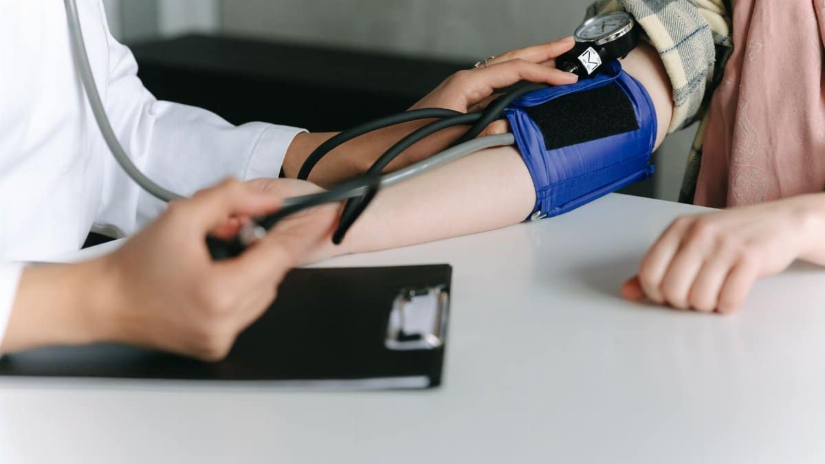 A healthcare worker uses a sphygmomanometer to check a patient's blood pressure in a medical office.