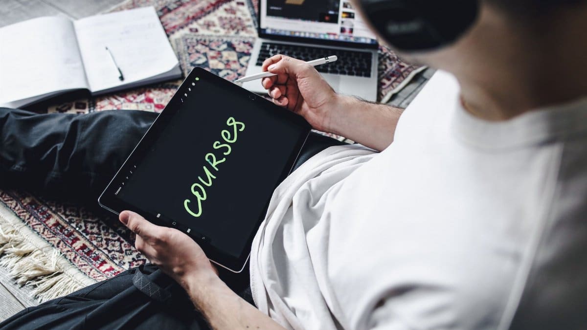Person studying online courses using a digital tablet while relaxing indoors with headphones.