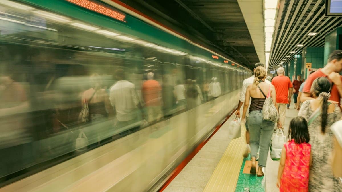 Commuters wait as a subway train passes by, capturing the hustle of urban travel.