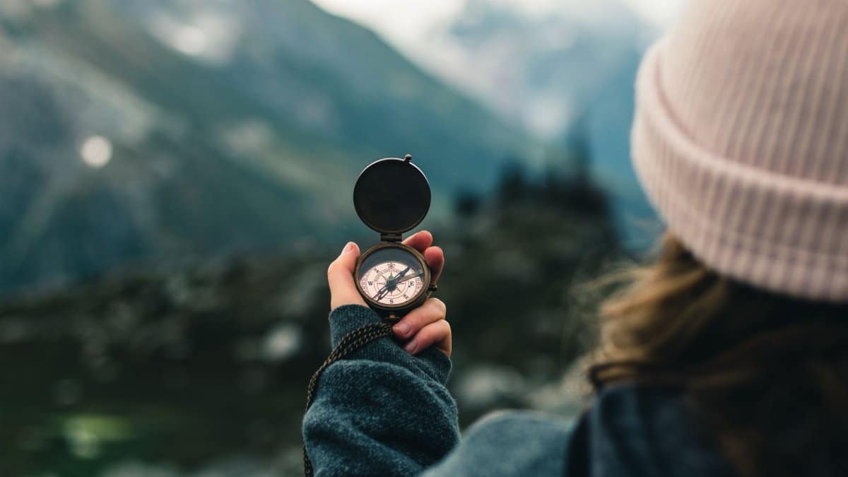 A woman holds a compass in the Canadian mountains, symbolizing adventure and exploration.