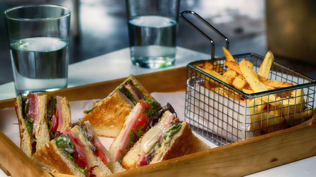 Tasty club sandwich and crispy fries served with glasses of water, perfect for a quick meal.