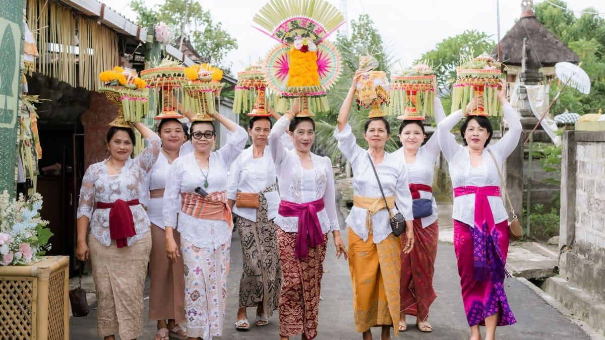 Balinese women in traditional attire carry ceremonial offerings during a cultural procession in Bali, Indonesia.