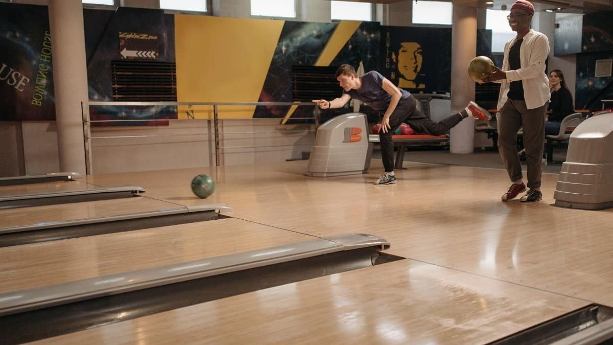 Two adults playing bowling indoors, highlighting leisure and sport in a fun atmosphere.