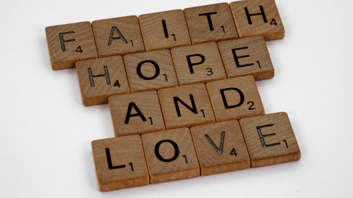 Scrabble tiles arranged to spell 'Faith Hope and Love' on a white background, perfect for positivity themes.