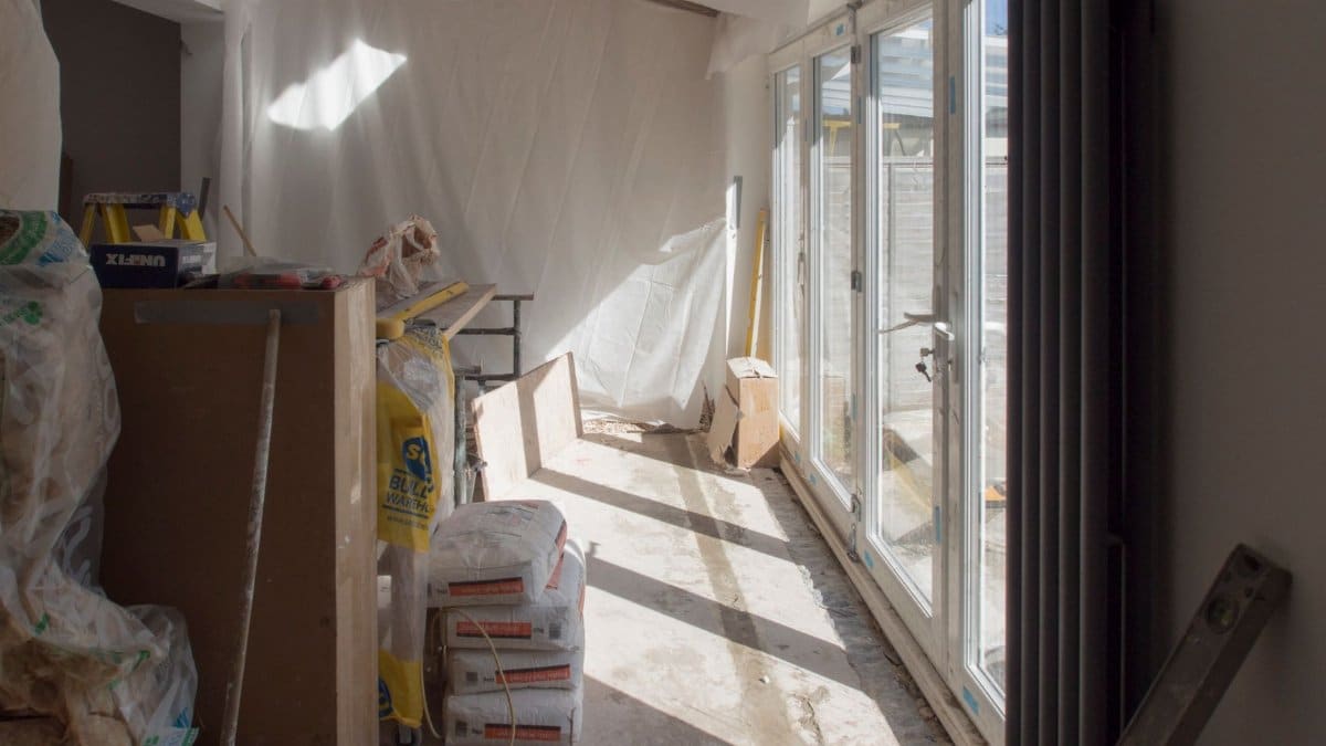 A construction area featuring renovation work in progress with large windows bringing in natural light.
