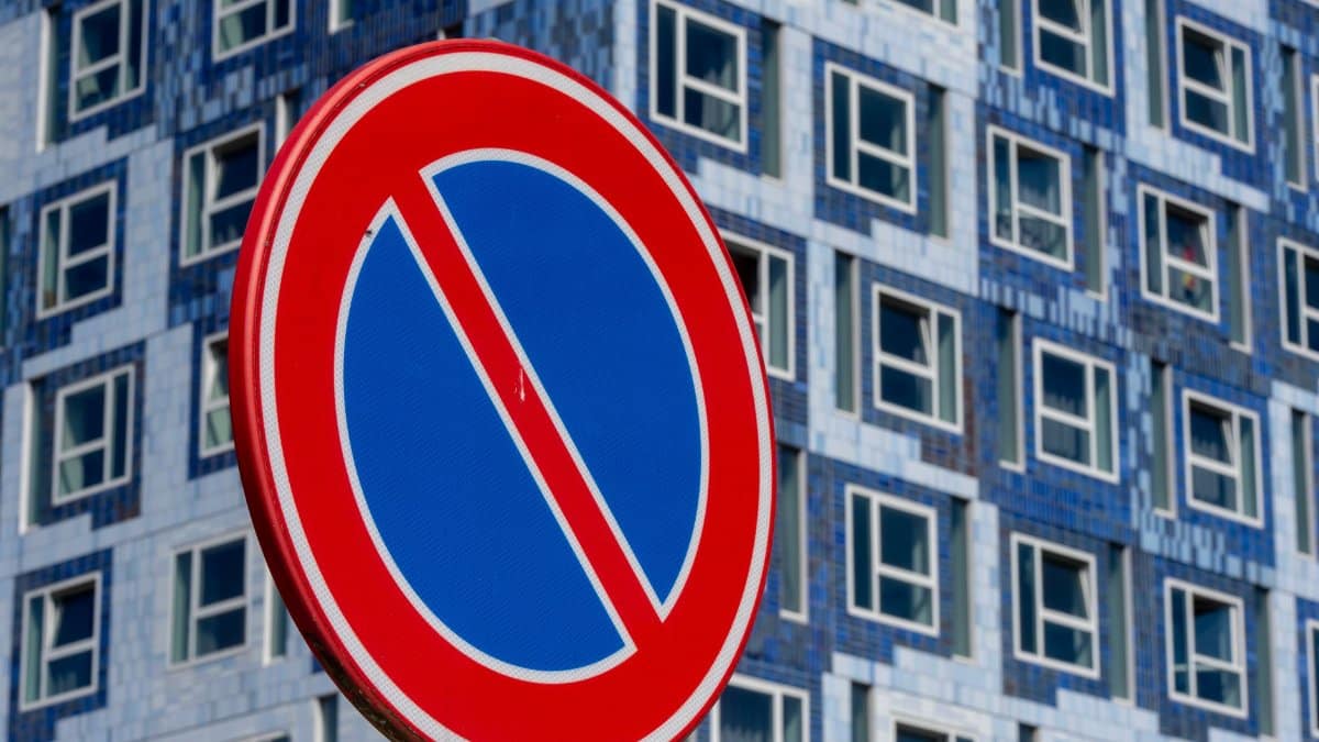 Bold no parking sign stands out against a modern building facade, emphasizing urban restrictions.