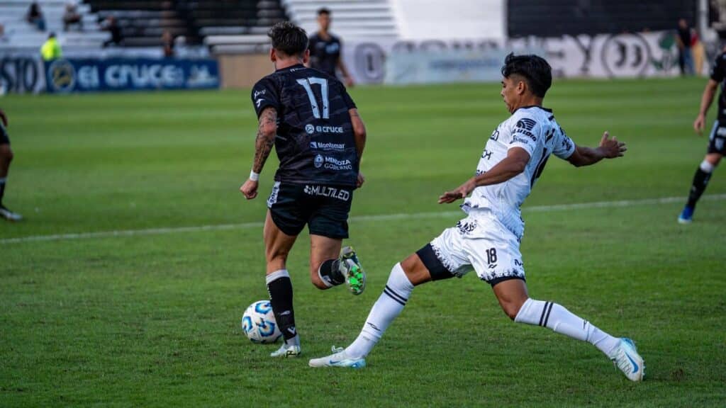 Two soccer players in action during an intense match on the grass field.