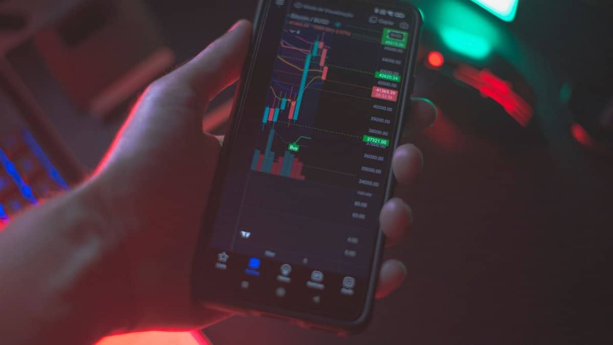 Hand holding smartphone displaying cryptocurrency trading app with financial data.