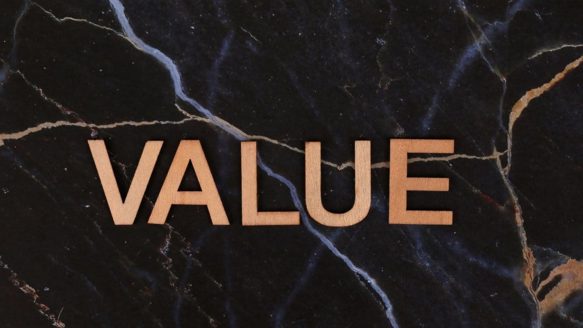 A close-up of wooden 'Value' letters placed on a dark marble background, emphasizing texture and concept.