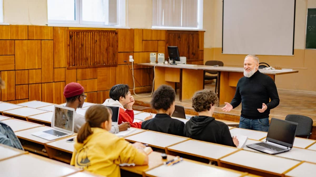 Students engaging with a professor in a university lecture hall, utilizing technology.