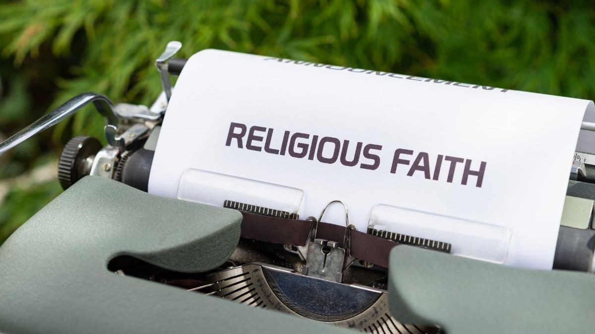 Close-up of a vintage typewriter typing 'Religious Faith' on paper outdoors.