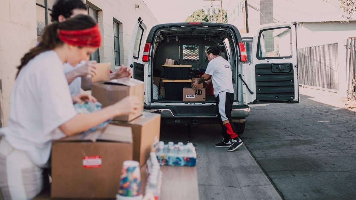 Volunteers organize and load boxes of donated supplies into a van for distribution.
