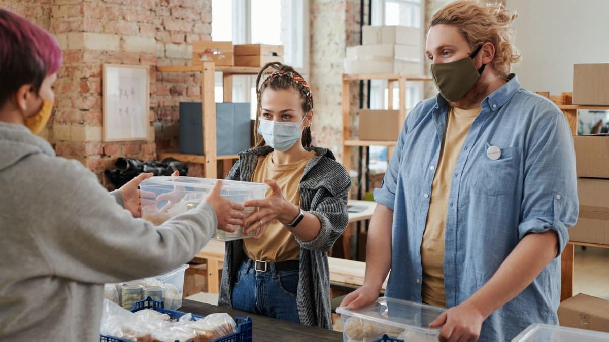Volunteers wearing masks distribute food in a donation center, focusing on charity and community support.